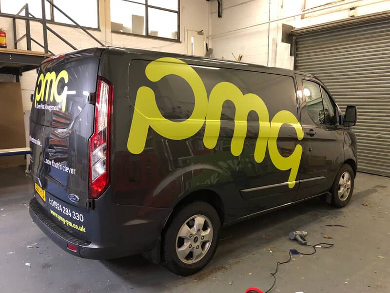 An image of the yellow PMG van graphics on a black van.